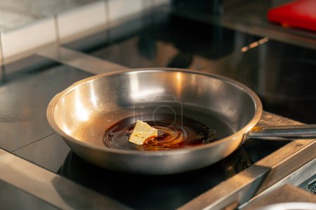 Foto de Primer plano en la cocina profesional el chef utiliza un cuchillo para distribuir aceite en una sartén - Imagen libre de derechos