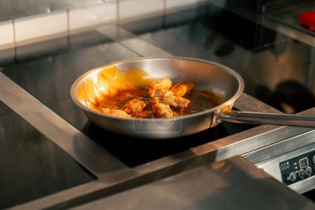 Foto de Primer plano de las alas de pollo fritas en salsa en una sartén en una cocina profesional - Imagen libre de derechos