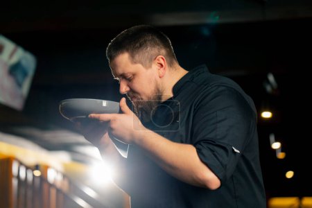 Téléchargez les photos : Un chef en noir dans un restaurant renifle la salade César qu'il a lui-même préparée - en image libre de droit
