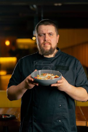 Téléchargez les photos : Gros plan dans un chef de restaurant dans un stand veste noire avec une salade préparée - en image libre de droit
