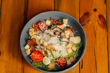 Téléchargez les photos : Close-up sur une table en bois il y a un plat préparé de salade césar dans une assiette grise - en image libre de droit