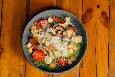 Téléchargez les photos : Close-up sur une table en bois il y a un plat préparé de salade césar dans une assiette grise - en image libre de droit