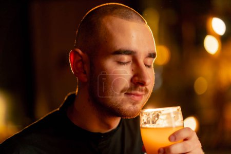 Téléchargez les photos : Gros plan sur une table de bar en bois un gars renifle un verre de bière lumière lumière d'éclairage chaud - en image libre de droit