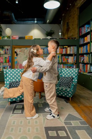 Photo for In a bookstore in the children area a beautiful girl and a boy peacefully share a book - Royalty Free Image