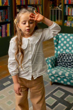 Téléchargez les photos : Dans une librairie dans la zone des enfants une belle fille est fatiguée d'étudier et de lire des livres - en image libre de droit