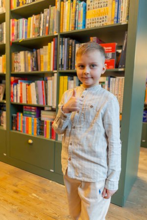 Photo for Close-up in a bookstore a handsome boy stands smiling among the bookshelves happy customer - Royalty Free Image