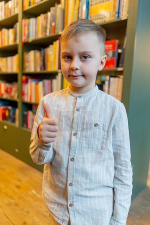 Foto de Primer plano en una librería un chico guapo está sonriendo entre las estanterías cliente feliz - Imagen libre de derechos