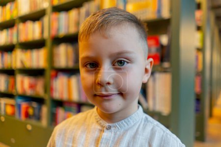 Nahaufnahme in einer Buchhandlung, ein gutaussehender Junge steht lächelnd zwischen den Bücherregalen, ein zufriedener Kunde