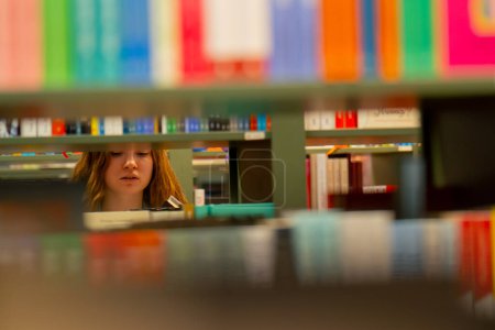 Téléchargez les photos : Fermer dans une librairie une jeune fille choisit un nouveau livre pour se préparer aux examens - en image libre de droit