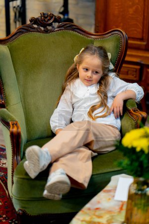 Photo for In a bookstore beautiful girl on a green antique sofa is relaxing and having fun - Royalty Free Image
