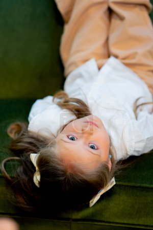 Photo for Close up in a bookstore beautiful girl on a green antique sofa is relaxing and having fun - Royalty Free Image