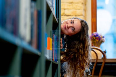 Foto de De cerca en una librería una joven elige un nuevo libro para ella preparándose para los exámenes - Imagen libre de derechos