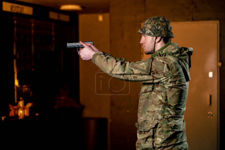 Photo for In a professional shooting range military man in ammunition takes aim from a cleaned pistol - Royalty Free Image