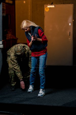 Foto de En un campo de tiro profesional un militar le dice y le muestra a una chica cuál es la postura correcta con una pistola - Imagen libre de derechos