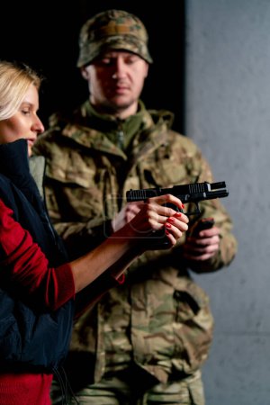 Foto de En un campo de tiro profesional un militar le dice y le muestra a una chica la postura correcta con una pistola es - Imagen libre de derechos