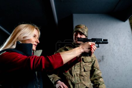Foto de Primer plano en un campo de tiro profesional un militar le dice y muestra a una chica la postura correcta con una pistola es - Imagen libre de derechos