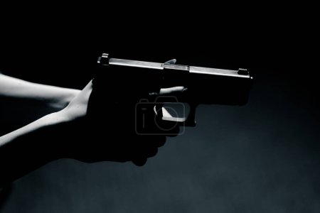 Foto de Primer plano de las manos femeninas que sostienen una pistola contraste luz disposición para disparar la posición correcta de las manos - Imagen libre de derechos