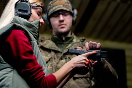 Téléchargez les photos : Dans un champ de tir professionnel, un militaire raconte et montre à une fille comment recharger un pistolet - en image libre de droit