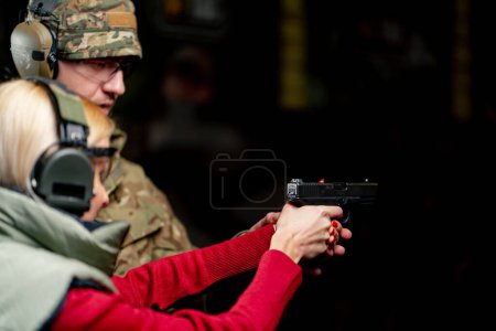 Foto de En un campo de tiro profesional militar controla la técnica de disparar una pistola el primer disparo - Imagen libre de derechos