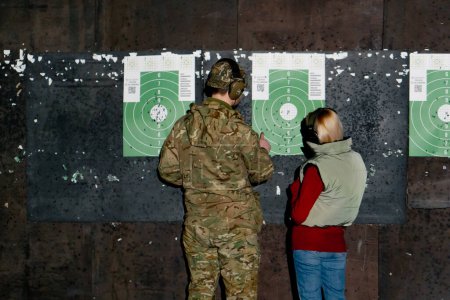 Foto de Un campo de tiro profesional un entrenador militar y una chica comprobar el objetivo de golpes - Imagen libre de derechos