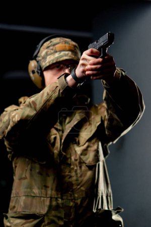 close-up at a professional shooting range military trainer in ammunition takes aim with a pistol