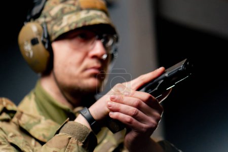 close-up at a professional shooting range military trainer in ammunition takes aim with a pistol