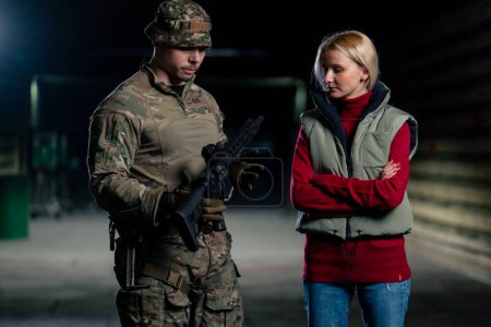 Téléchargez les photos : Dans un champ de tir professionnel, un instructeur militaire dit à une fille comment manipuler correctement les armes de l'OTAN - en image libre de droit