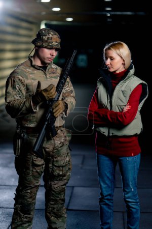 Téléchargez les photos : Dans un champ de tir professionnel, un instructeur militaire dit à une fille comment manipuler correctement les armes de l'OTAN - en image libre de droit