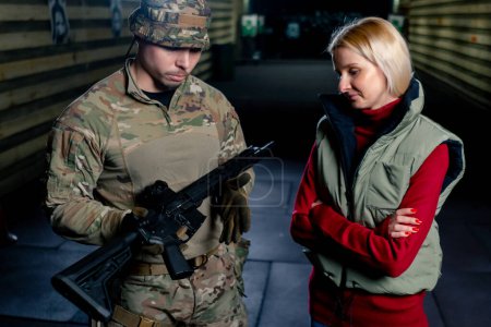 Foto de En un campo de tiro profesional un entrenador militar le dice a una chica cómo manejar correctamente las armas de la OTAN - Imagen libre de derechos