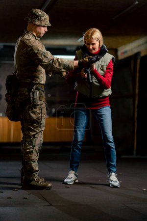 Foto de En un campo de tiro profesional un entrenador militar da un rifle barato de la OTAN para el entrenamiento - Imagen libre de derechos