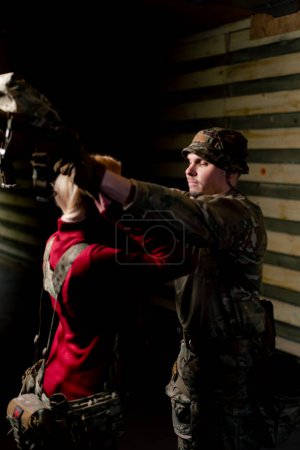 Foto de En un campo de tiro profesional un entrenador militar le pone munición táctica a una chica barata - Imagen libre de derechos