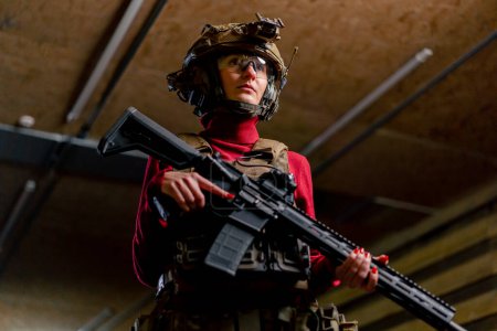 Photo for Low shot at a professional shooting range a girl in tactical ammunition stands with a NATO rifle - Royalty Free Image