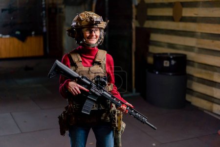 Téléchargez les photos : Dans un champ de tir professionnel, une jeune fille souriante portant des munitions tactiques et un fusil de l'OTAN - en image libre de droit