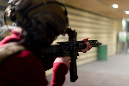 Foto de En un campo de tiro profesional una joven en munición táctica se está preparando para disparar - Imagen libre de derechos