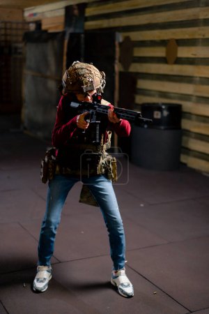 Foto de En un campo de tiro profesional una joven en munición táctica se está preparando para disparar - Imagen libre de derechos