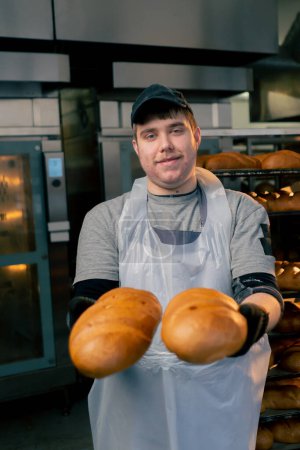 Téléchargez les photos : Dans une cuisine professionnelle boulangers mains en gants noirs tenir du pain et souriant - en image libre de droit