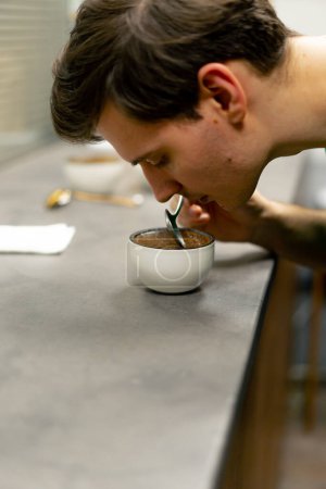Téléchargez les photos : Fermer dans une usine de torréfaction de café dans le bol de cuisine de café en remuant café reniflant - en image libre de droit