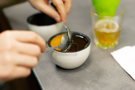 Foto de Primer plano en una fábrica de tostado de café en la cocina, un tazón de café se recoge con cucharas de espuma - Imagen libre de derechos