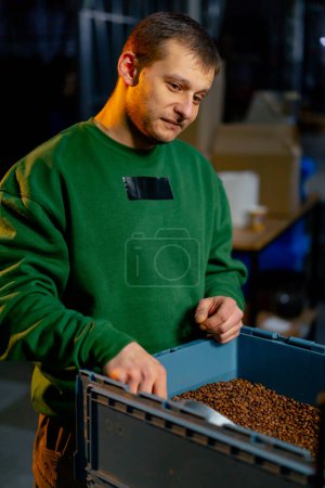 Foto de Retrato en una fábrica de tostado de café un trabajador saca café con una pala - Imagen libre de derechos