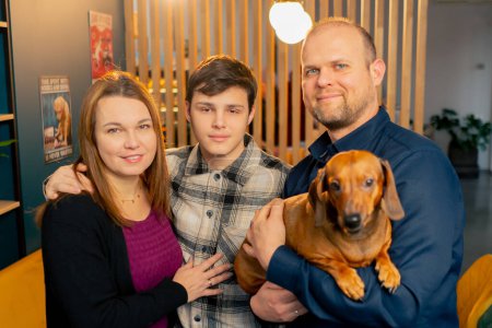 Foto de Foto familiar con un pequeño dachshund en sus brazos en un café un momento feliz para toda la familia - Imagen libre de derechos