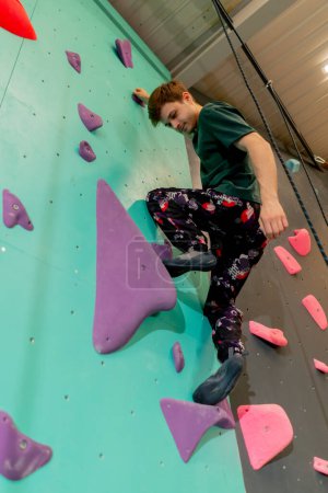 Photo for Low shot at the climbing wall a young handsome professional trainer climbs the wall without insurance - Royalty Free Image