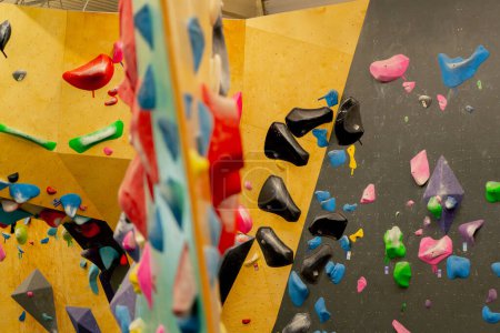 Téléchargez les photos : Fermer un professionnel beau nouveau grimpeur pour l'entraînement et l'entraînement de différentes couleurs de mur - en image libre de droit