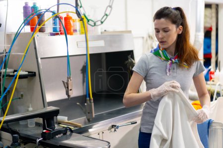 Téléchargez les photos : Professional dry cleaning young girl bleaches a stain on white jacket professional equipment - en image libre de droit