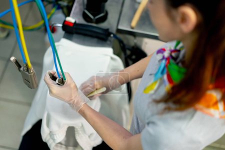 Téléchargez les photos : Top shot nettoyeur à sec professionnel une jeune fille enlève une tache à l'aide d'un crayon chimique spécial avec un vapeur - en image libre de droit