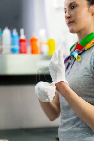 Photo for Close-up of a professional dry cleaner, a young girl puts on fabric white gloves for cleanliness of work - Royalty Free Image