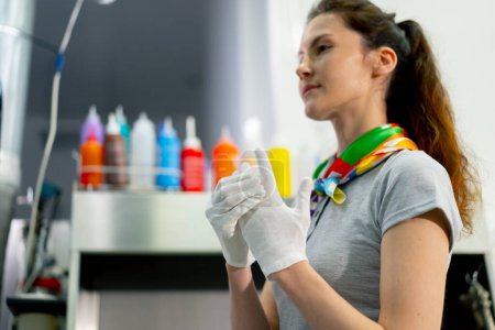 Photo for A professional dry cleaner, a young girl puts on fabric white gloves for cleanliness of work - Royalty Free Image