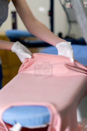 Photo for Close-up professional dry cleaning young girl lays out a pink jacket for ironing professional equipment - Royalty Free Image