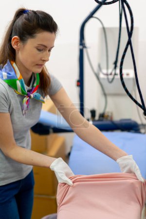 Photo for Professional dry cleaning young girl lays out a pink jacket for ironing professional equipment - Royalty Free Image