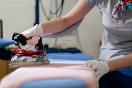 Photo for Close up professional dry cleaning young girl ironing pink with professional iron with steam - Royalty Free Image