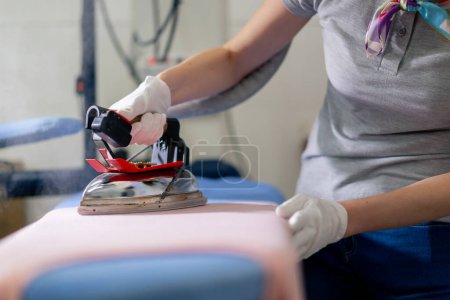 Photo for Close up professional dry cleaning young girl ironing pink with professional iron with steam - Royalty Free Image